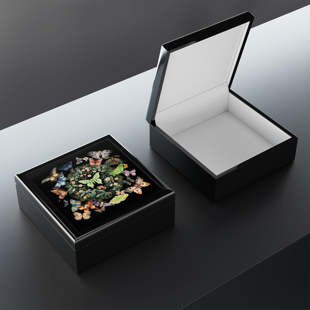 Black luna moth jewelry box shown closed beside an open matching box with an empty pale-lined interior.