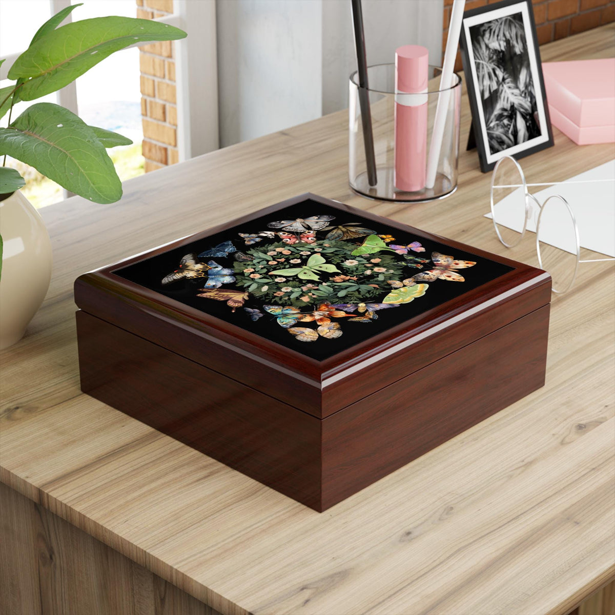 Closed brown wooden jewelry box with a luna moth and butterfly lid viewed at an angle on a desk.