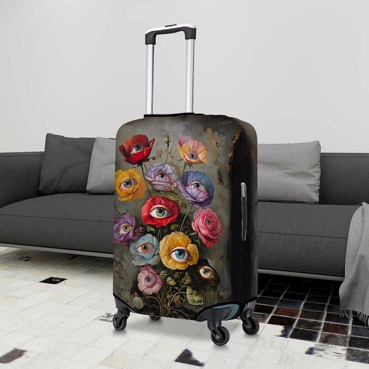 A hard-shell rolling suitcase standing upright in a living room setting, featuring a dark vintage-style floral print with large colorful eyes in the petals. A gray sofa and patterned floor are visible in the background.
