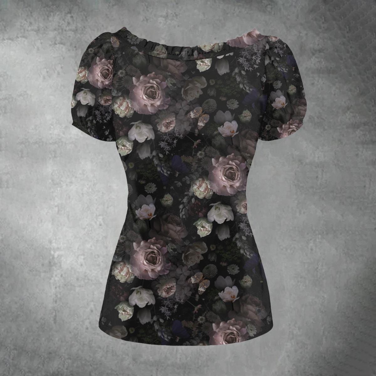 A short-sleeve blouse with a dark floral print, featuring muted pink, gray, and white roses on a black background, displayed against a textured gray backdrop.