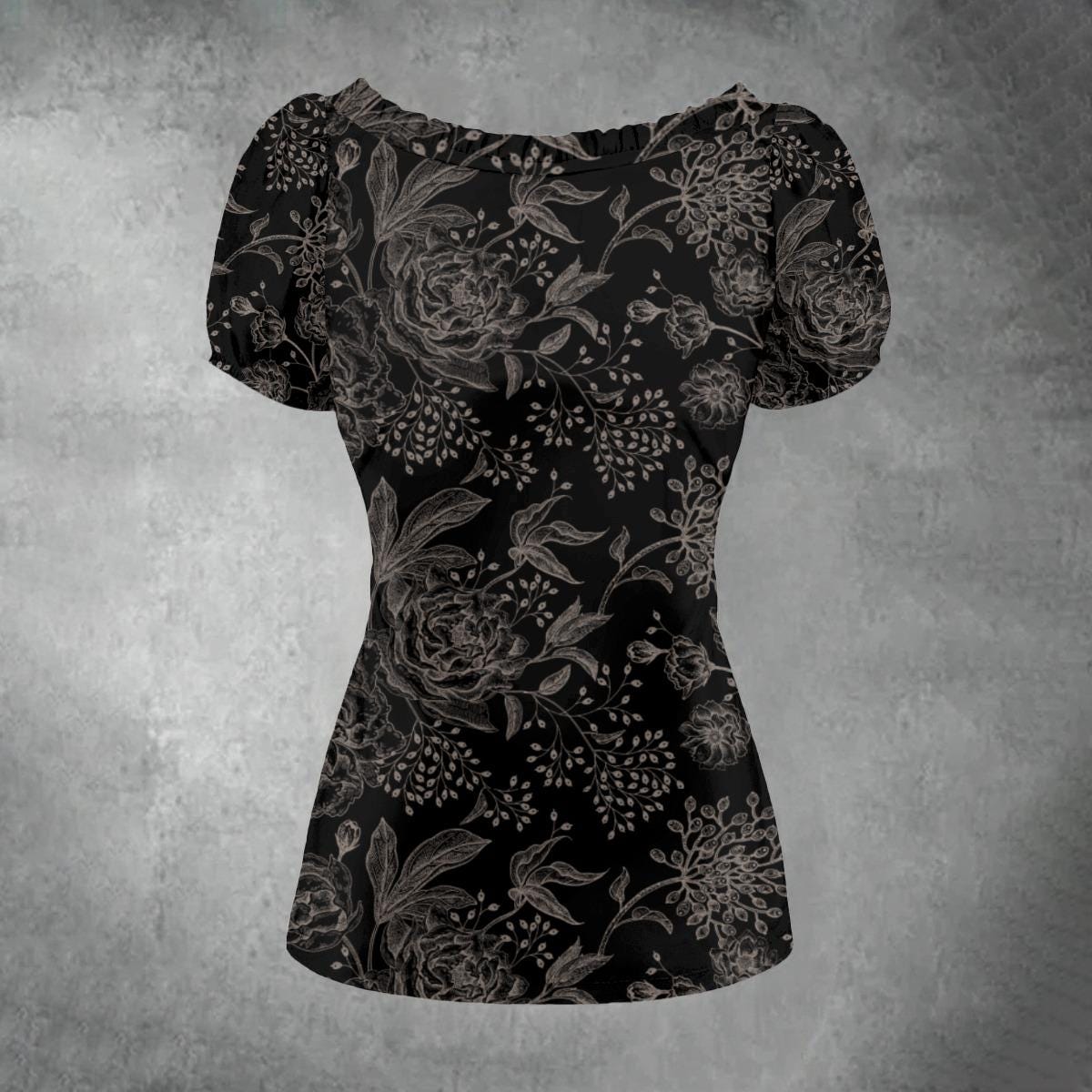 A black short-sleeve blouse with a gray floral and botanical pattern, featuring a boat neckline and puffed sleeves, displayed against a textured gray background.