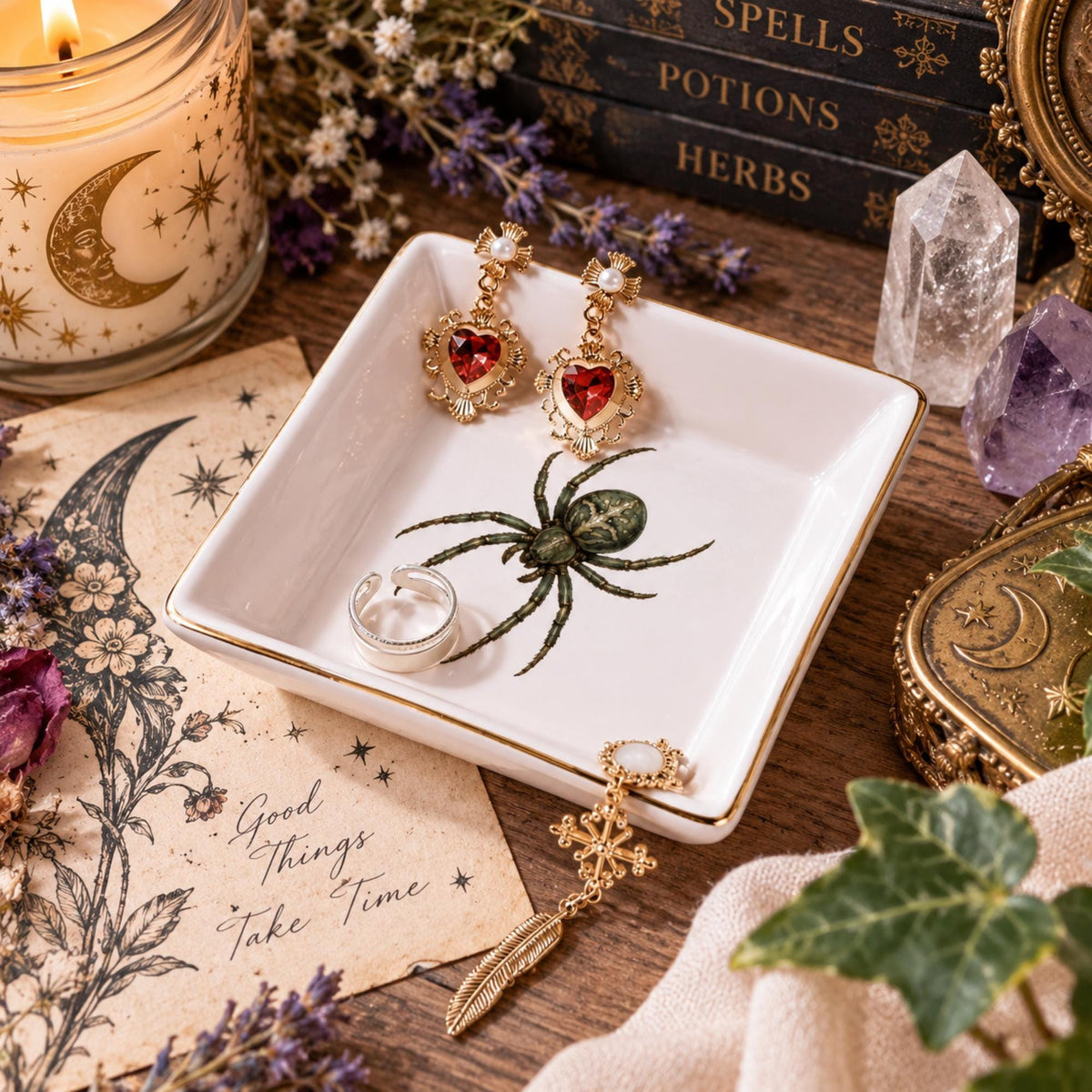 Angled view of a white gold-rimmed spider jewelry dish holding red heart earrings and a silver ring.