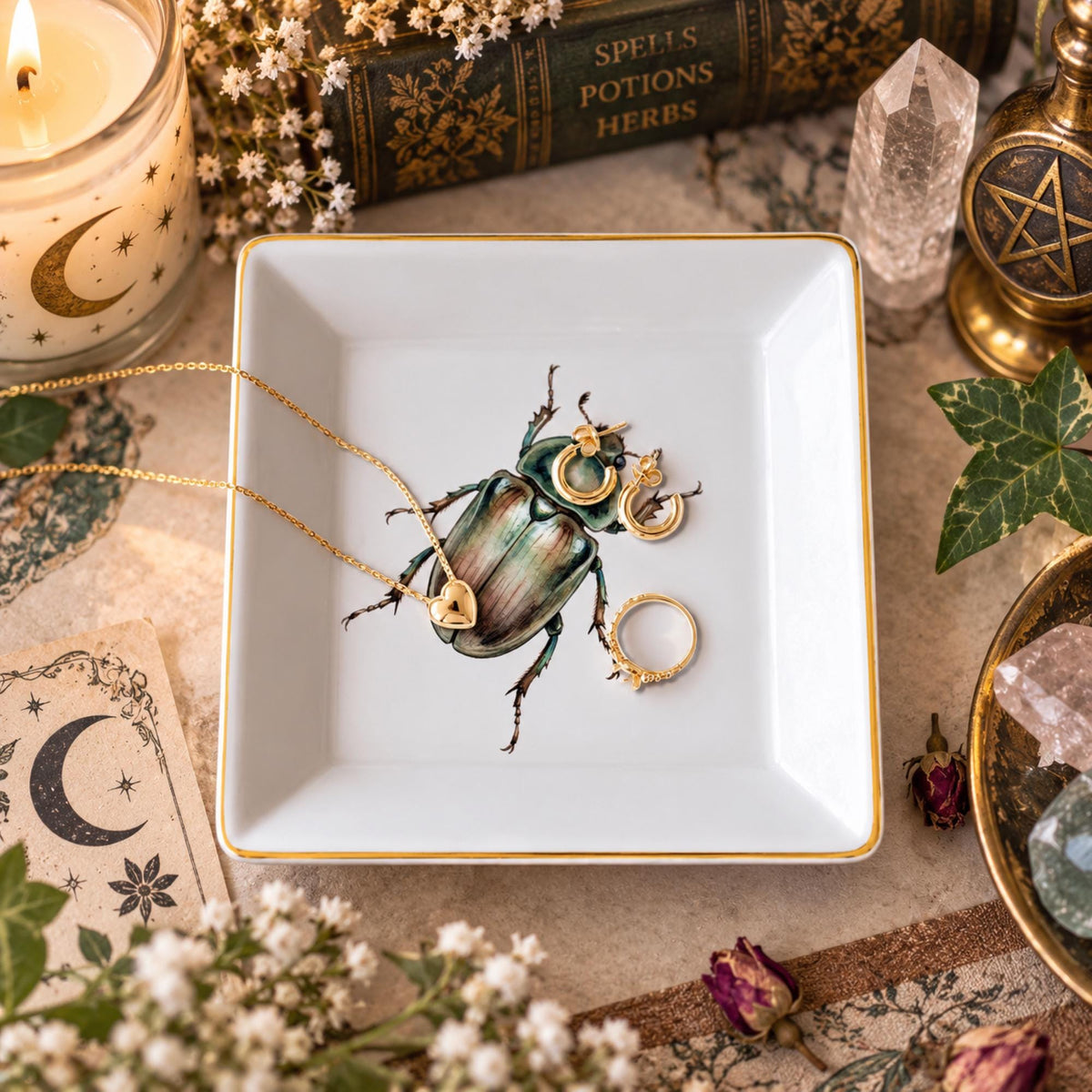 Overhead view of a white square gold-rimmed beetle jewelry dish holding a necklace and earrings and a ring.
