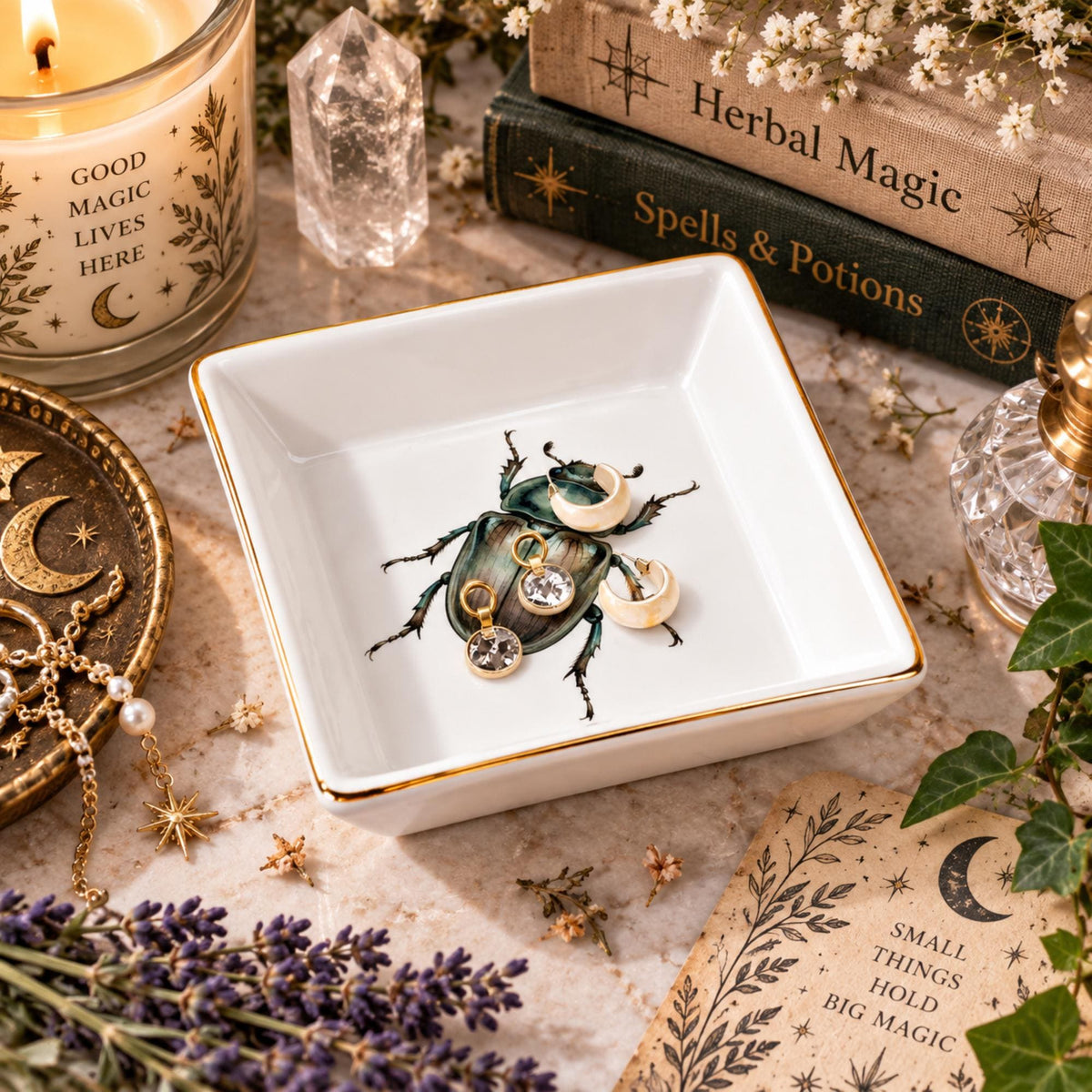 Angled view of a white gold-rimmed beetle jewelry dish holding crescent earrings and small gemstone pendants.